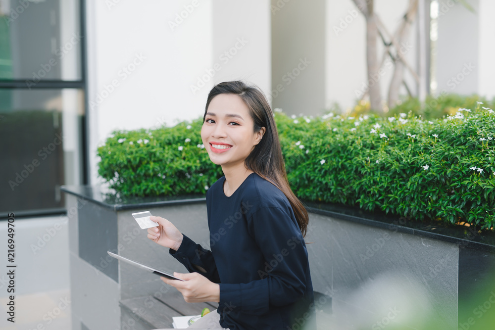 一位年轻漂亮的亚洲商业女性坐在办公楼外的长椅上