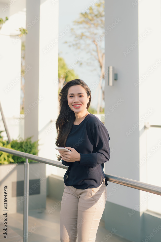 城市里的夏天。漂亮的年轻女人在户外拿着智能手机。