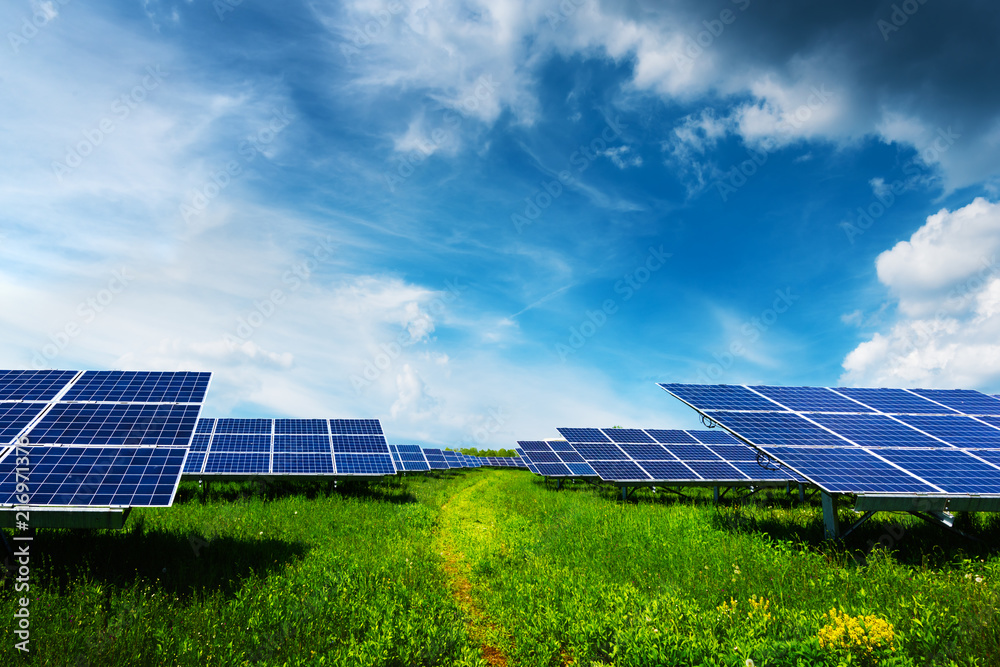 Solar panel on blue sky background. Green grass and cloudy sky. Alternative energy concept