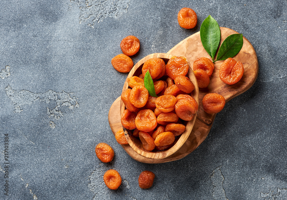 Dried apricots with green leaves on gray background. Top view.