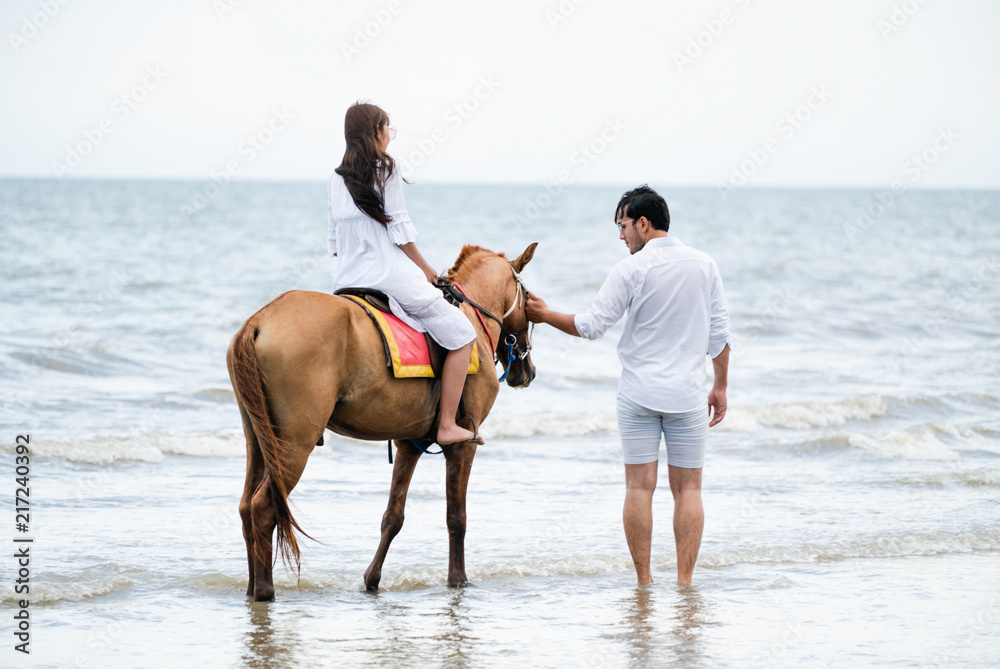 年轻夫妇在热带海滩上骑马。