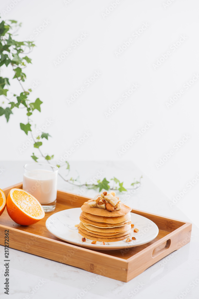 一堆美味的煎饼，盘子里放着巧克力、蜂蜜、坚果和香蕉片，餐巾上放着