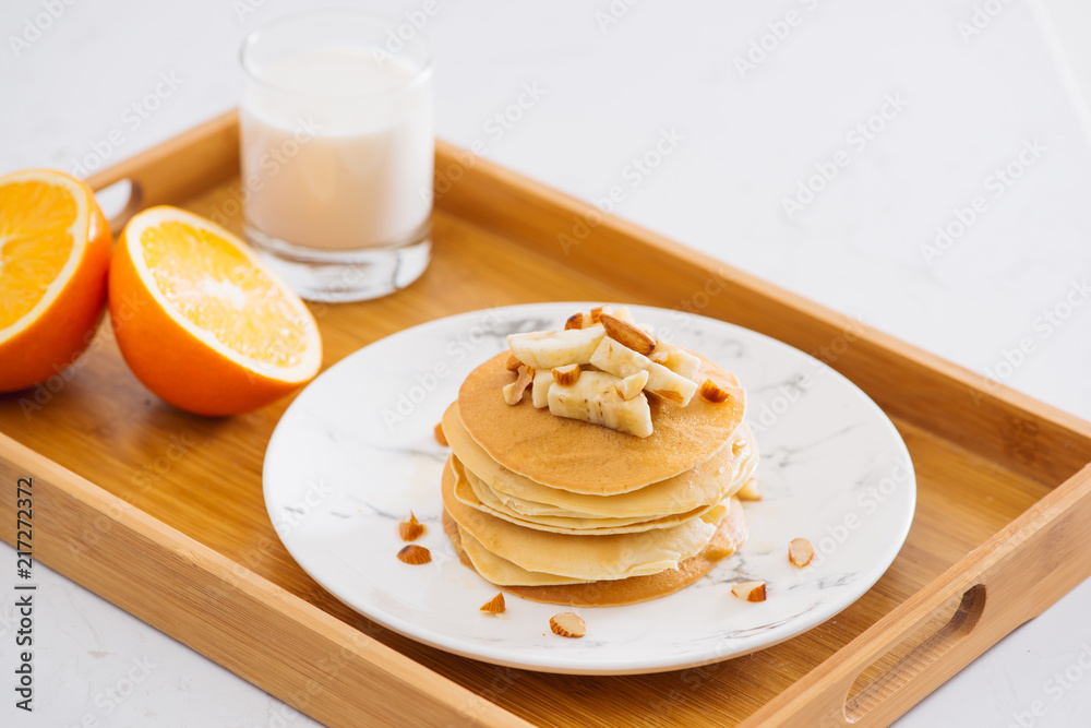 一堆美味的煎饼，里面有巧克力、蜂蜜、坚果和香蕉片，放在石头背上的盘子里