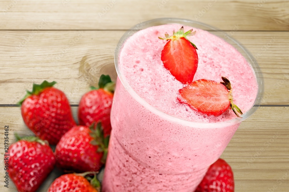 Glass of strawberry smoothie on wooden table