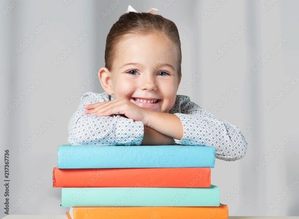 Little cute girl with books near green