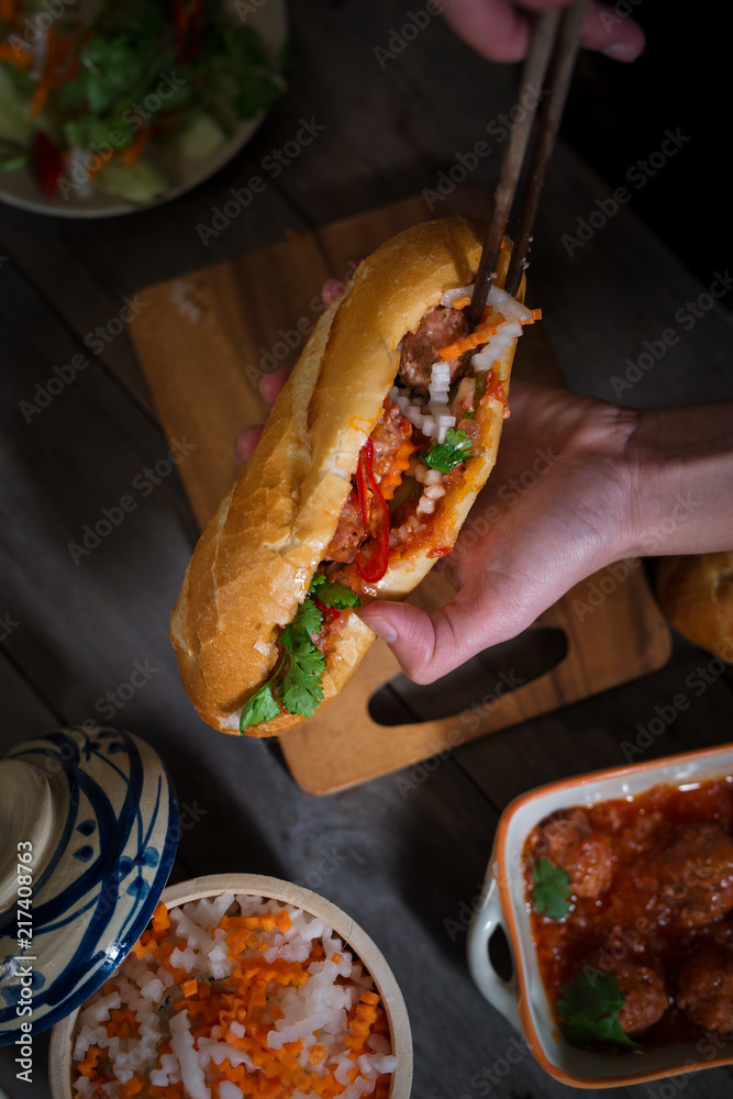 Vietnamese sandwich bread with meatballs in tomato sauce and radish, carrot pickle, cucumber, corian