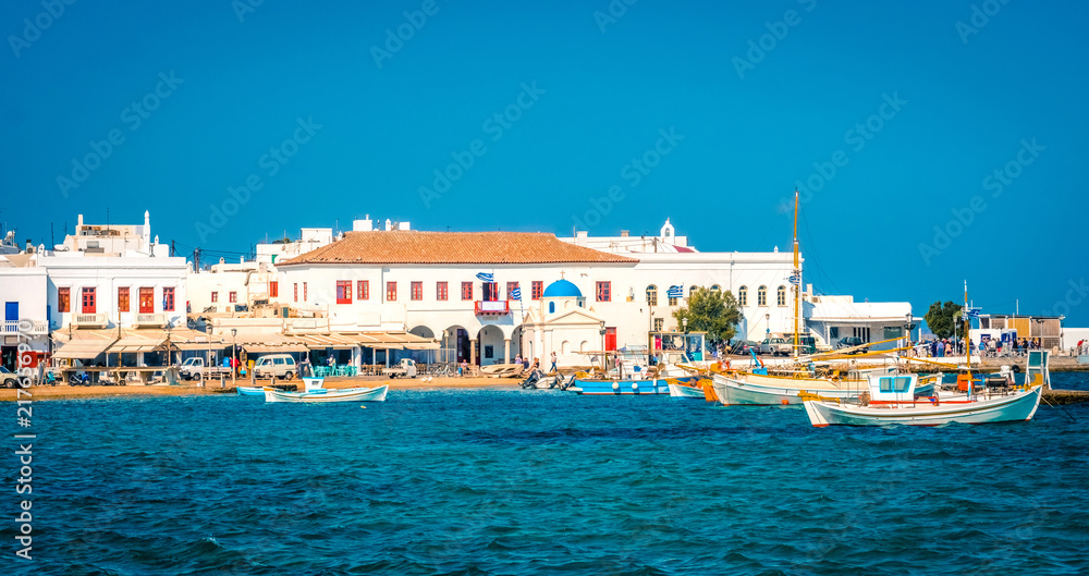 Beach with boats near pier, vew from the sea in Mykonos, Greece