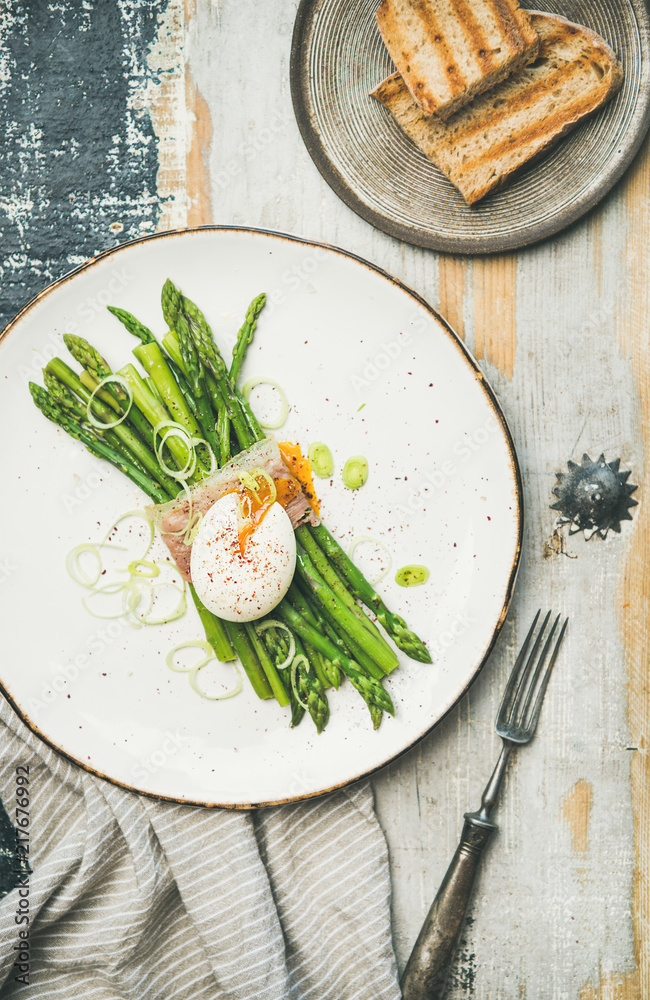 Healthy breakfast. Flat-lay of green asparagus with soft-boiled egg, leek and bacon served in white 