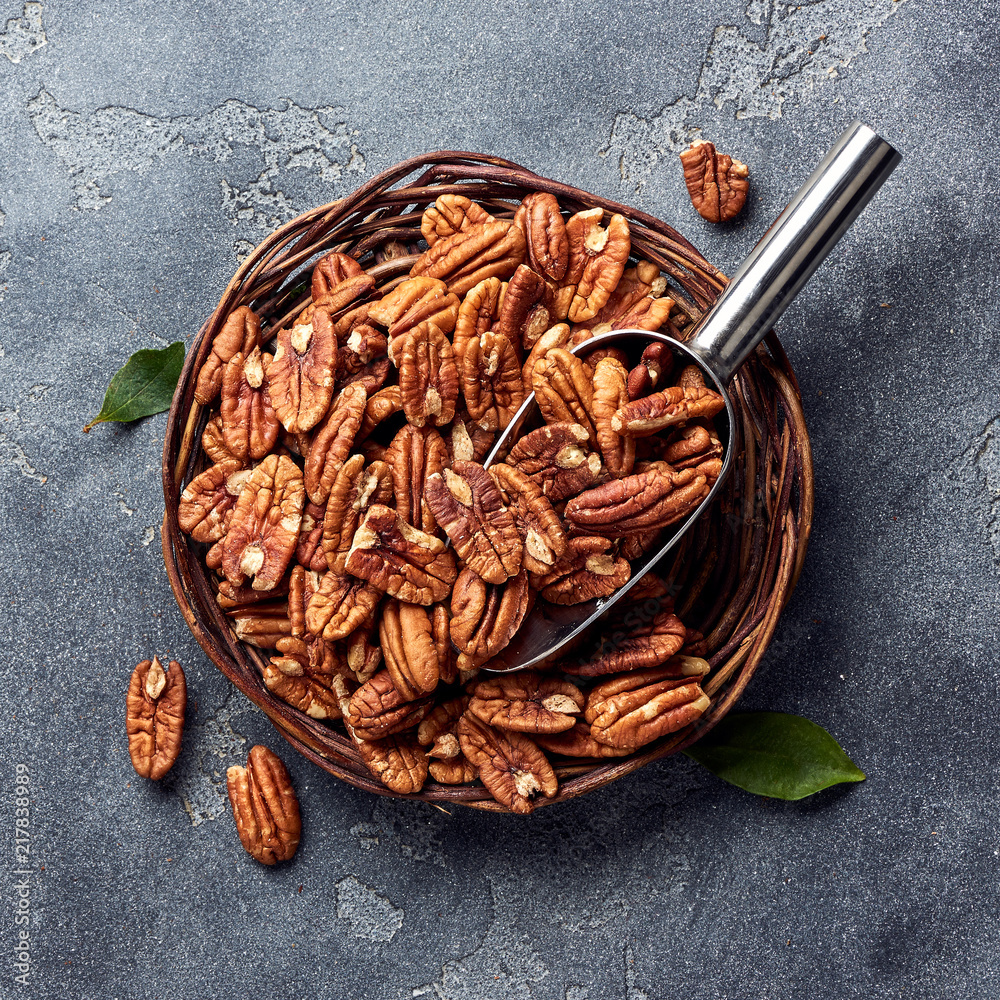 Pecan nuts and scoop on gray table