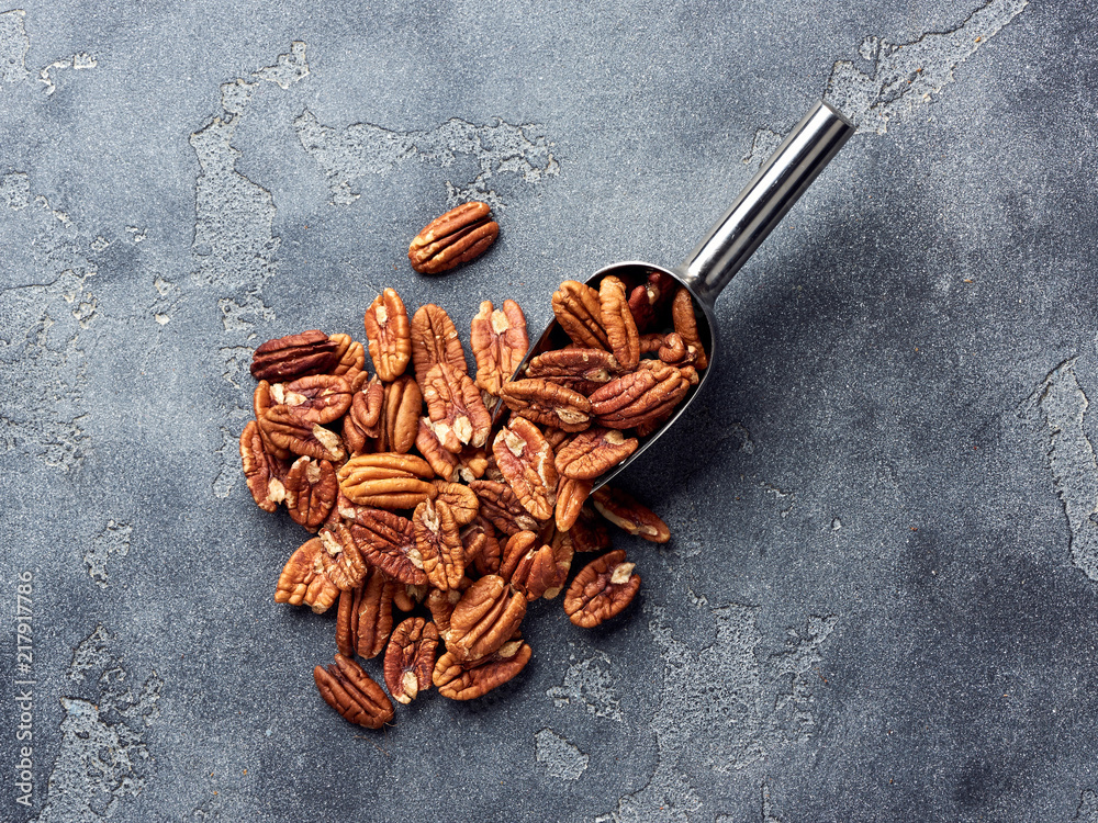 Pecan nuts and scoop on gray table