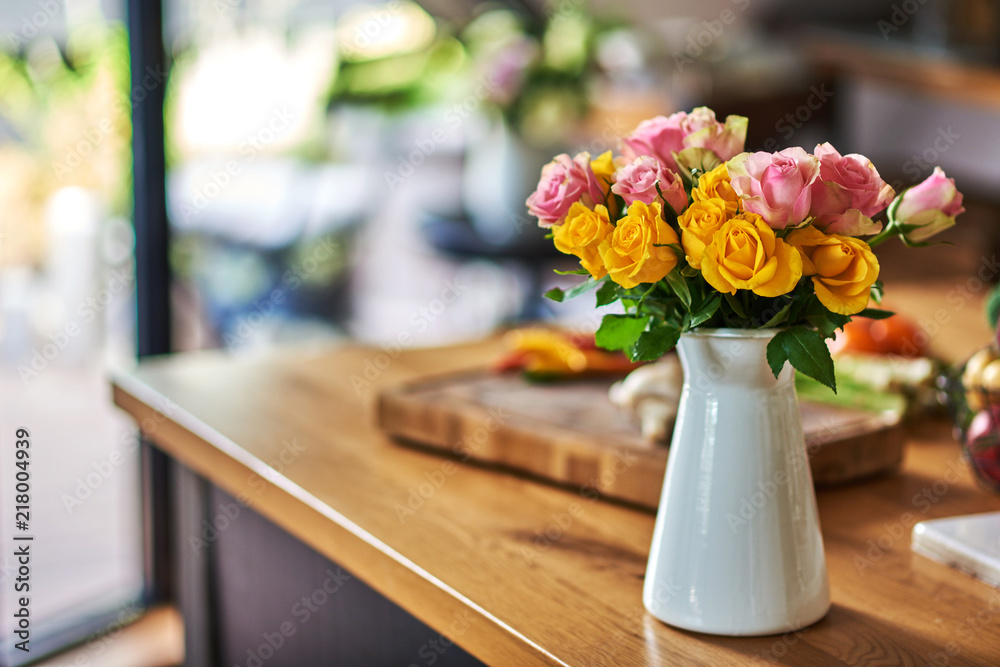 Yellow and pink roses on kitchen background.