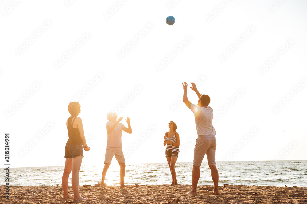 Friends outdoors on the beach play volleyball having fun.