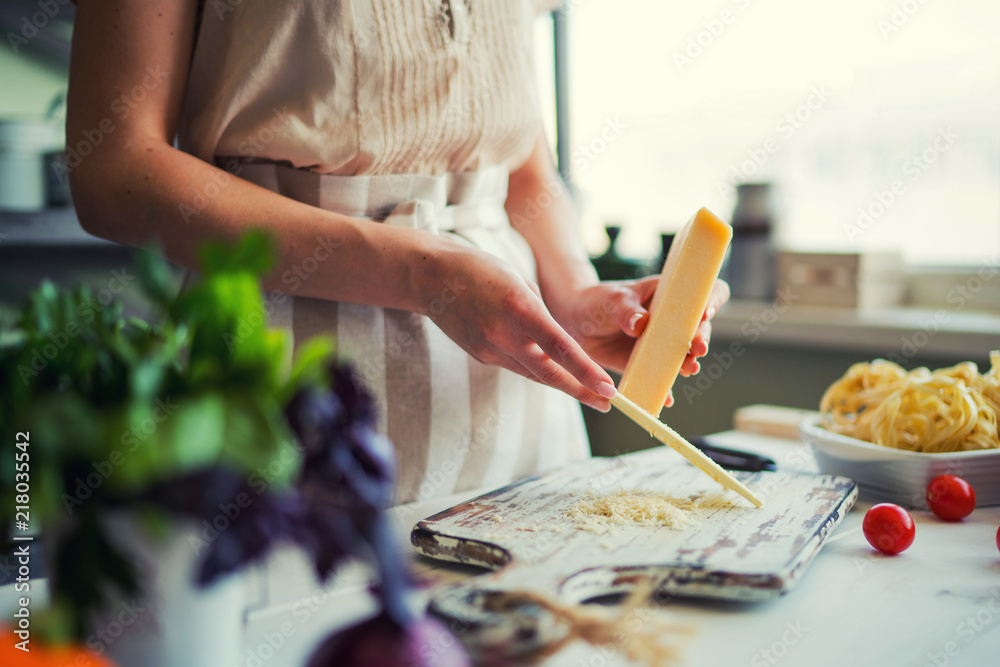 Young woman in apron at table with vegetables. Сooking meal at home, preparing lunch from fresh orga