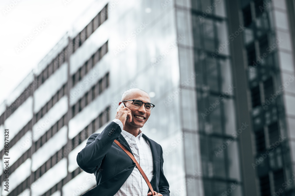 Businessman talking over mobile phone walking outdoors