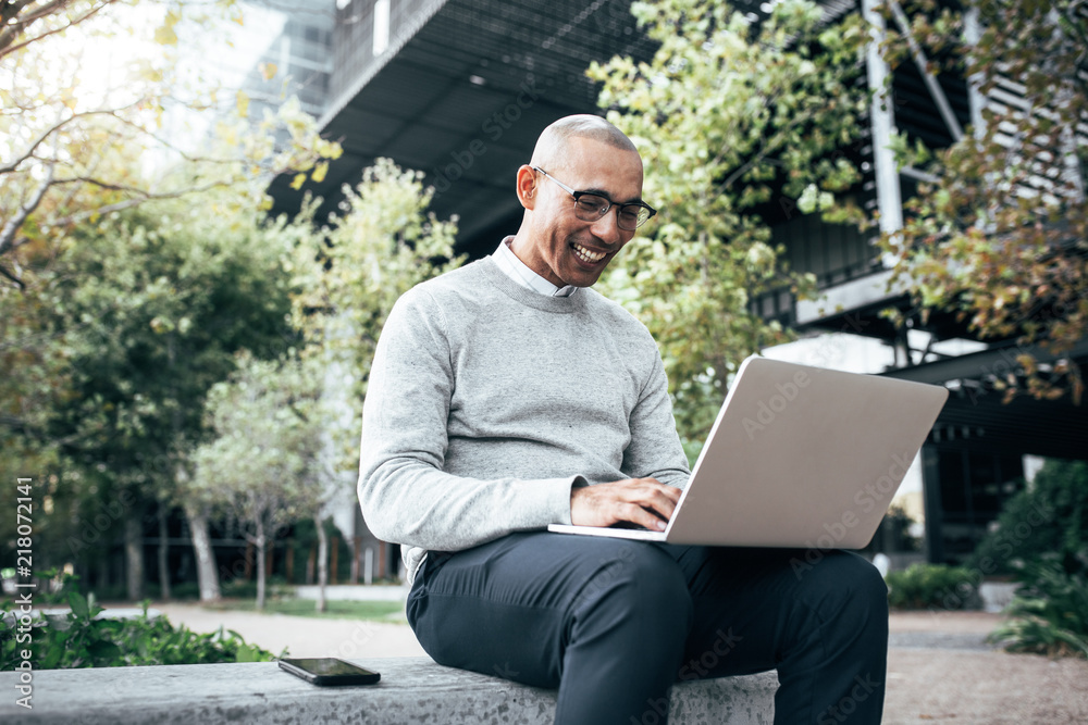 Businessman working on laptop computer sitting outdoors