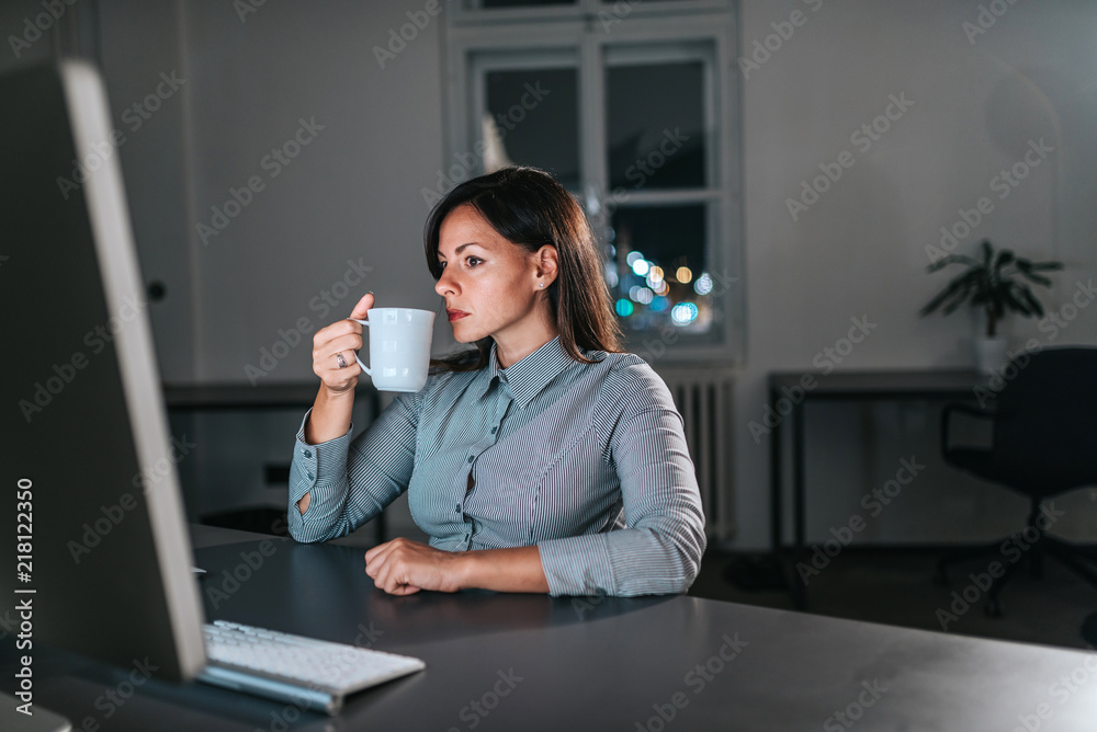 女商人在深夜工作时喝咖啡的特写图片。复制空间。