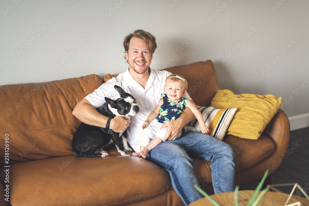 Young father with baby daughter on sofa at home