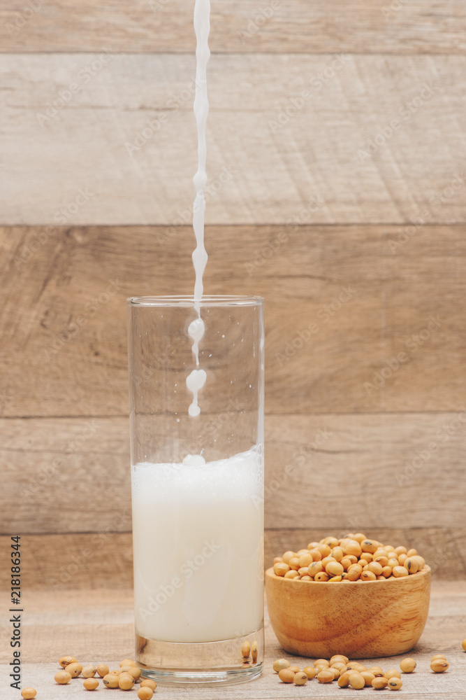 Glass with soy milk and soy bean on wooden background