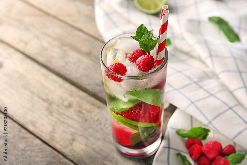 Glass of fresh raspberry mojito on wooden table