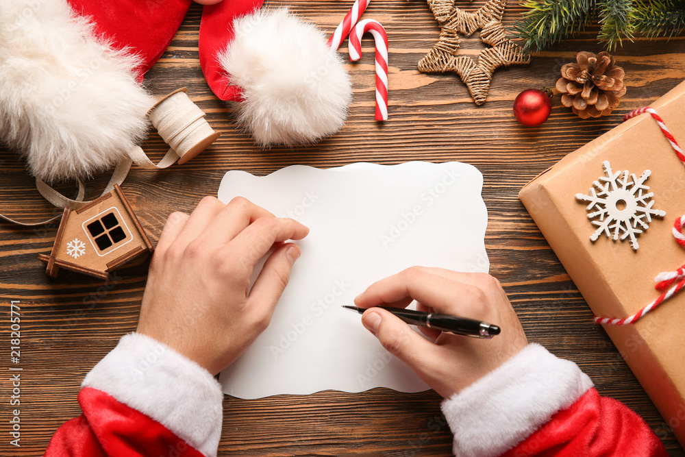 Santa Claus writing letter on wooden table