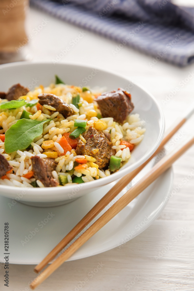 Delicious boiled rice with meat and vegetables in bowl on table