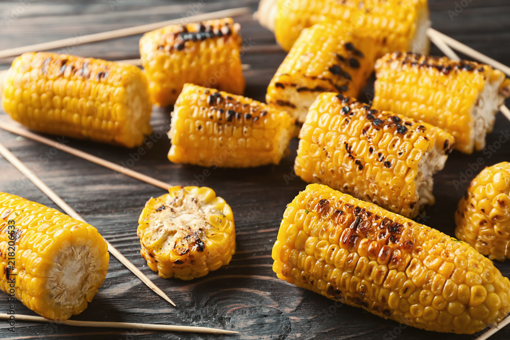 Delicious grilled corn on wooden table, closeup