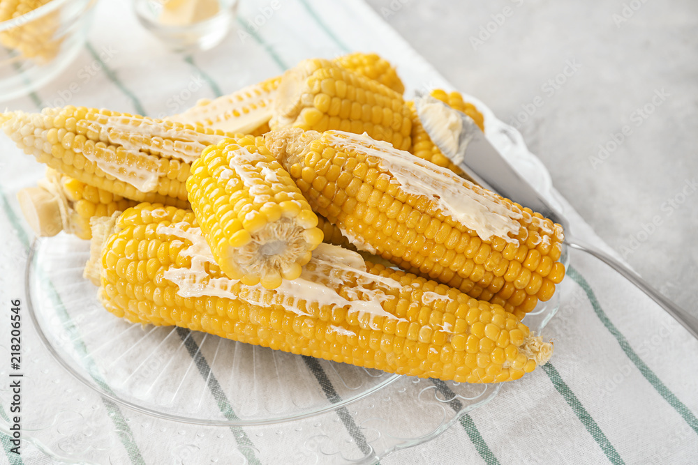 Tasty corn cobs with butter on glass plate