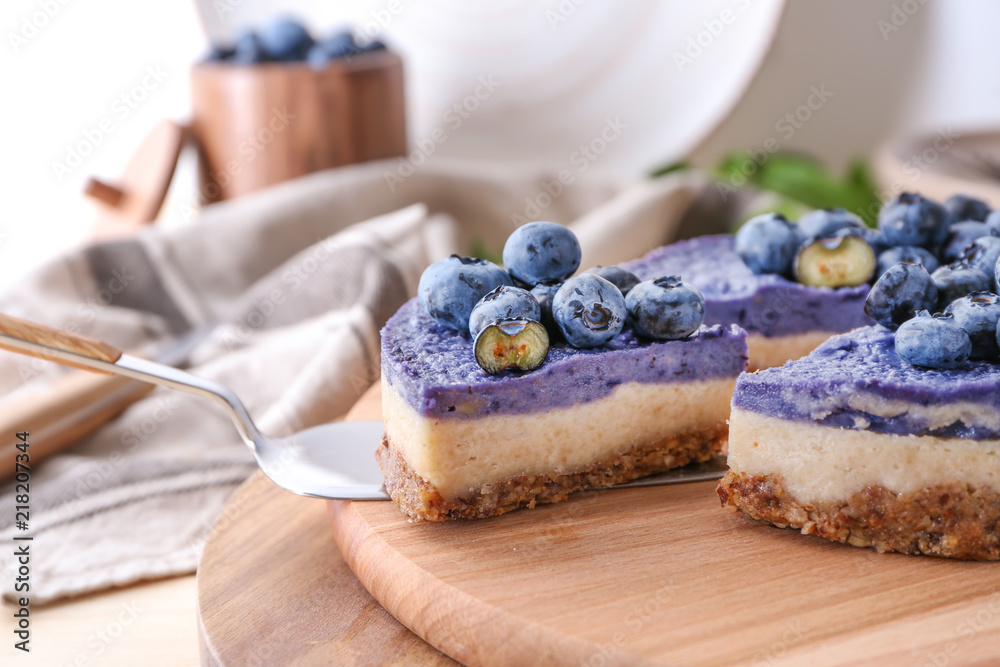 Taking of tasty cheesecake with blueberries from board by using shovel, closeup