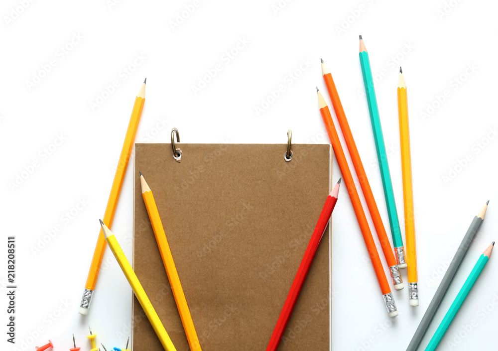 Notebook and pencils on white background