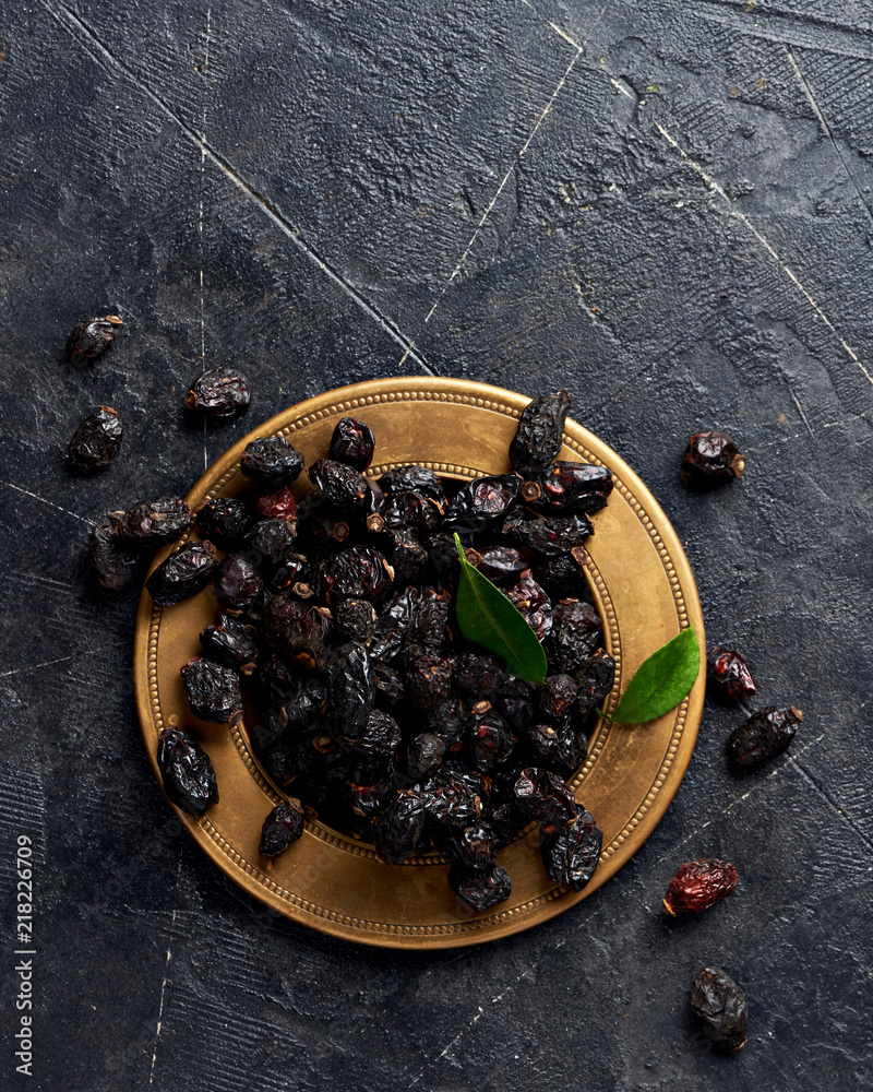 Dried rosehip on plate over black background.