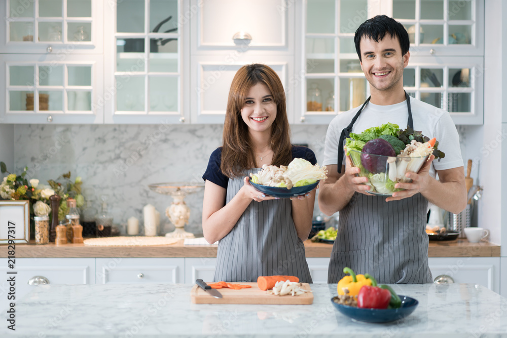 Young Asian couple preparing food together at counter in kitchen. Happy love couple concept.