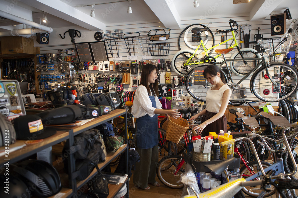 女性店員が自転車にカゴを取り付けようとしている