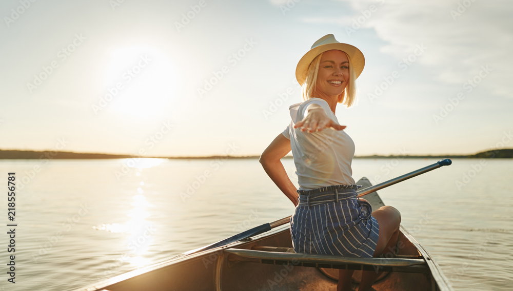 下午晚些时候，微笑的女人在湖面上划独木舟