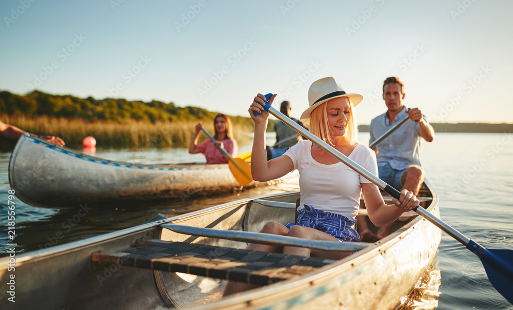 Smiling young woman canoeing with friends on a sunny afternoon