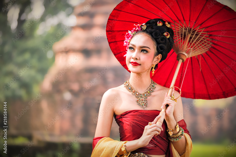 美丽的泰国女孩穿着传统服装，打着红色雨伞，作为泰国寺庙，公共广场在哪里