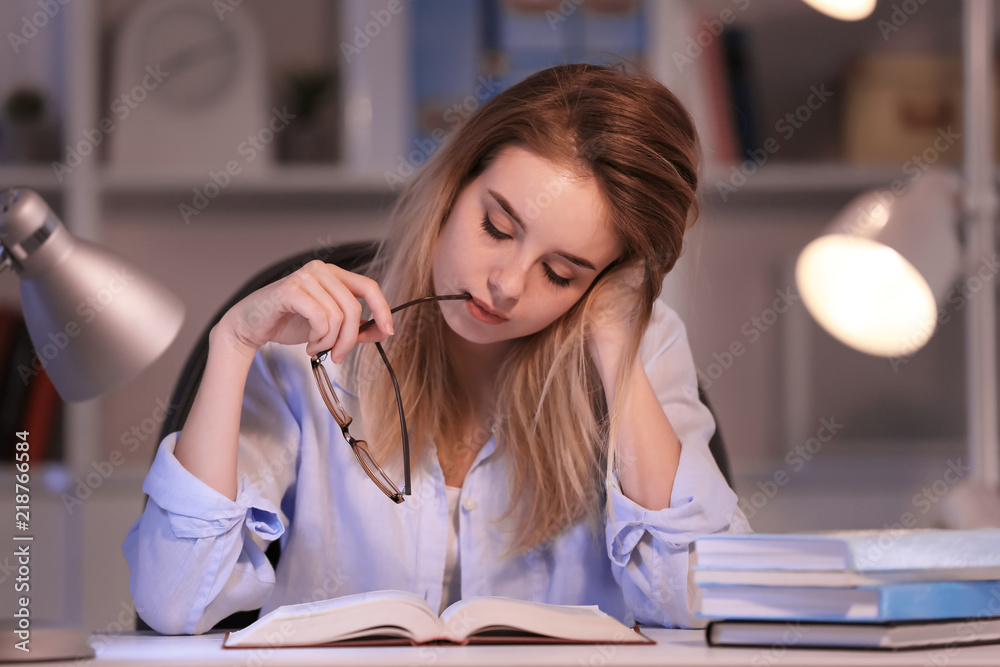 年轻女子晚上在餐桌旁看书