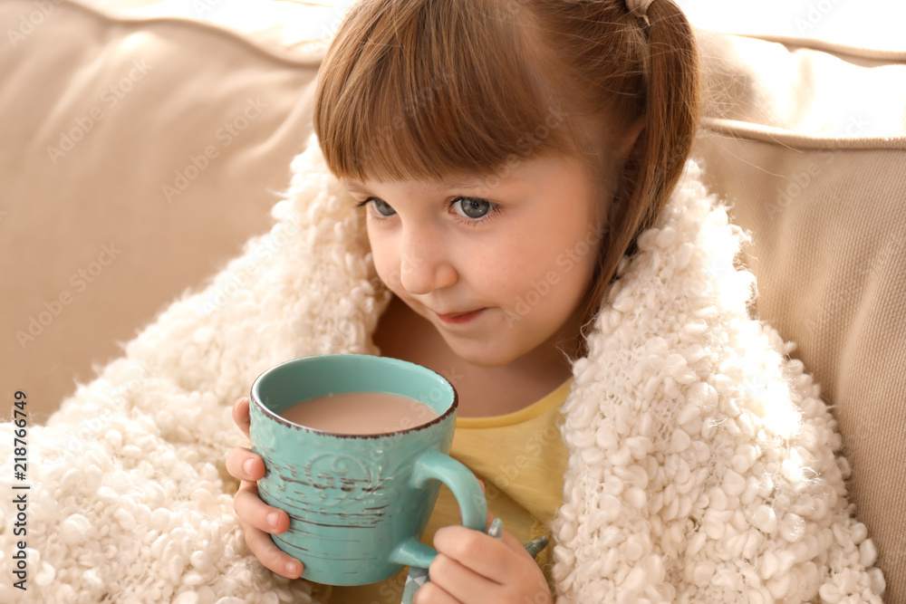 Cute little girl with cup of hot cocoa drink at home