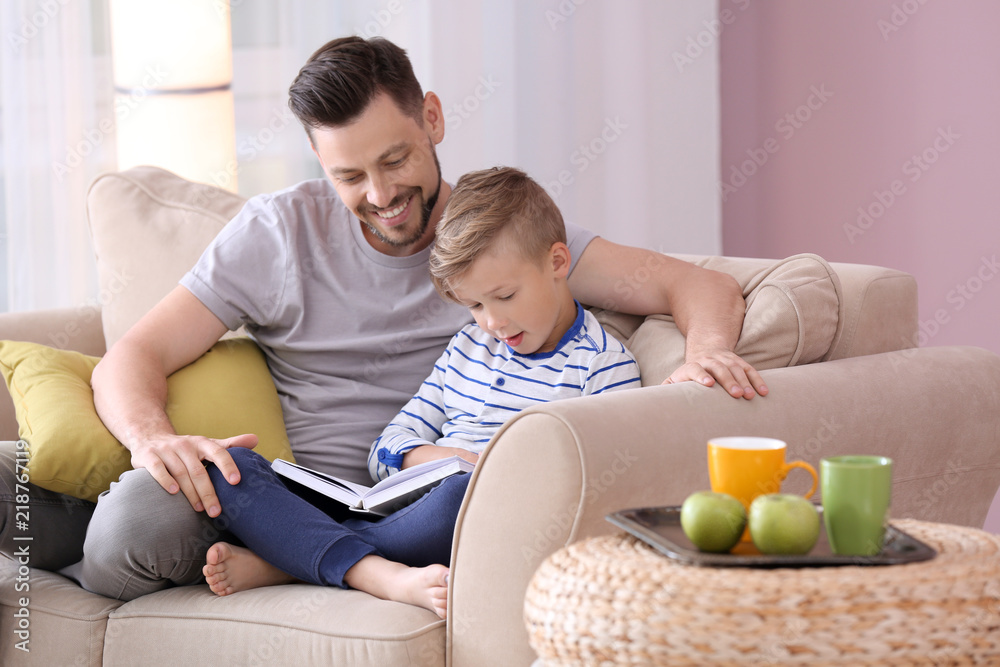 Father and his son reading book together at home