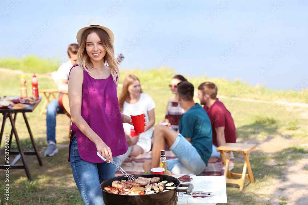 在户外烧烤架上烹饪肉类和蔬菜的年轻女性