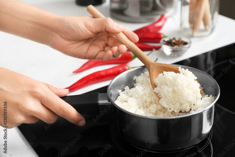 女人用勺子在炖锅里搅拌米饭，特写