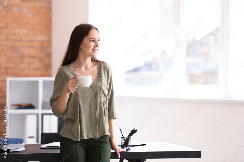 Young businesswoman drinking coffee in office