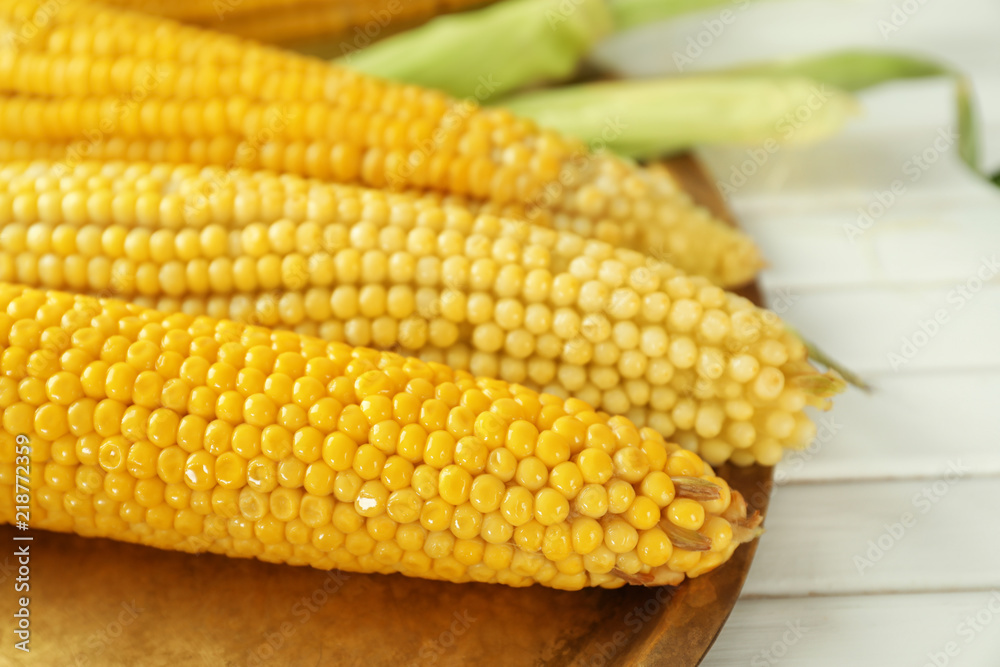 Tray with tasty corn cobs on wooden background, closeup