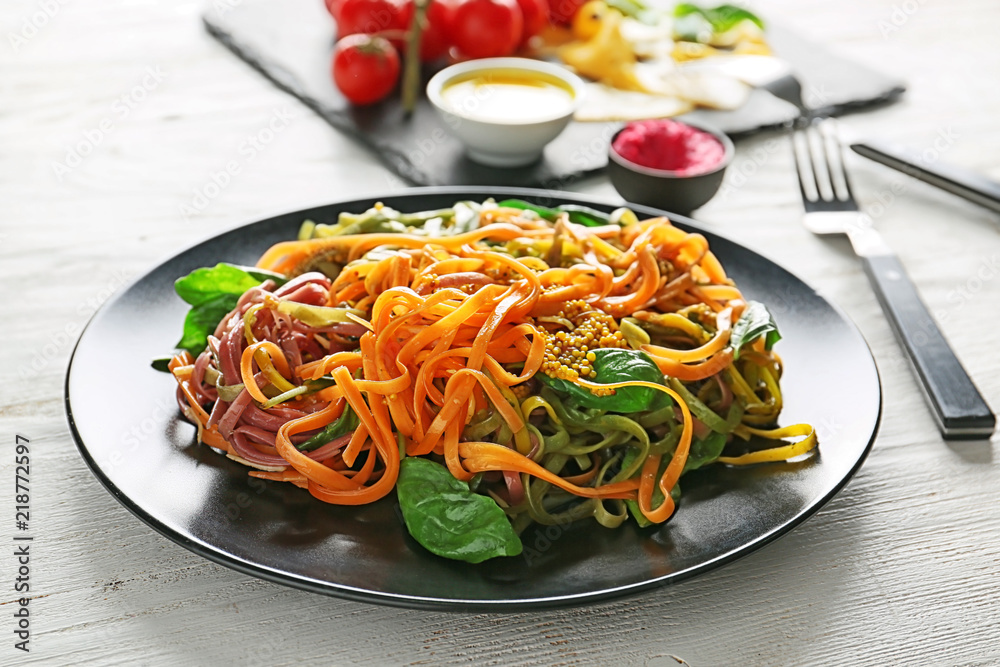 Plate of delicious colorful pasta with basil and mustard on wooden table