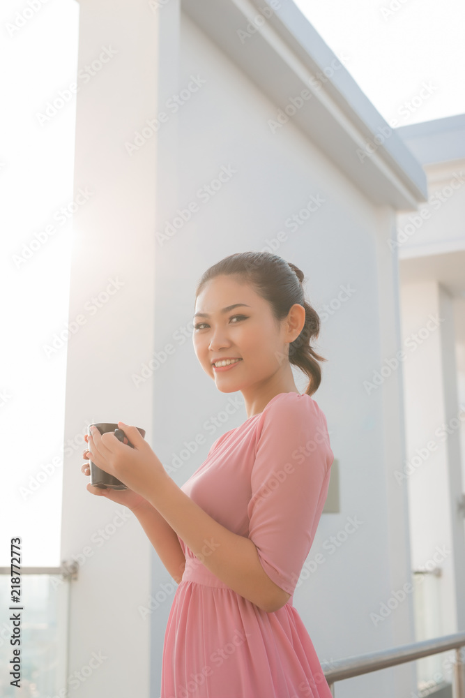 年轻女子拿着咖啡杯微笑着看着镜头