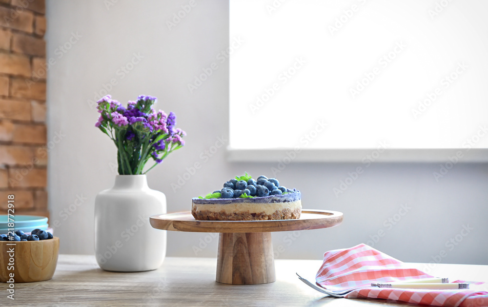 Tasty blueberry cheesecake and flowers on wooden table