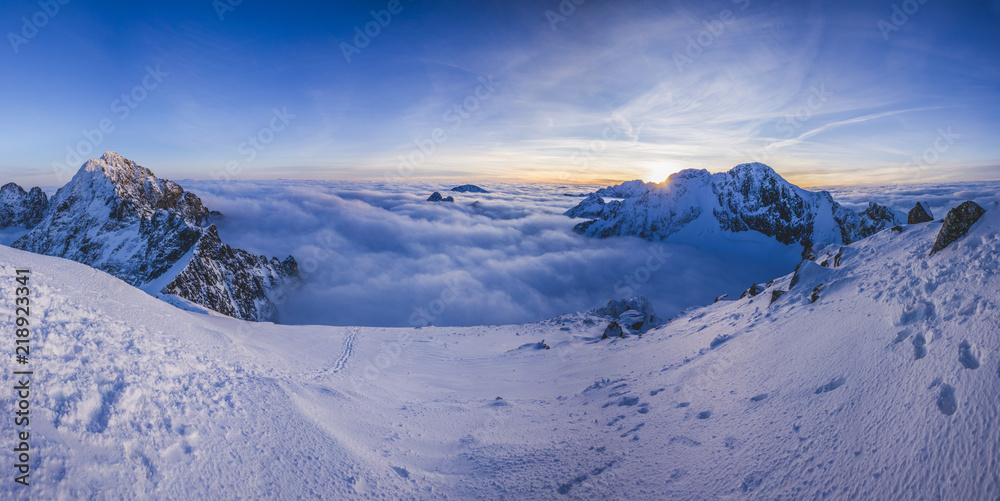 冬季高山景观的全景。冬季积雪覆盖的山脉中的日落或日出。