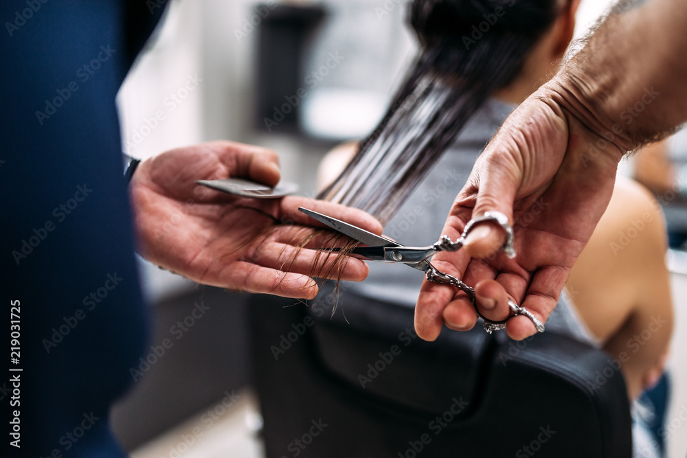 Hairdressers hands cutting hair. Close-up.