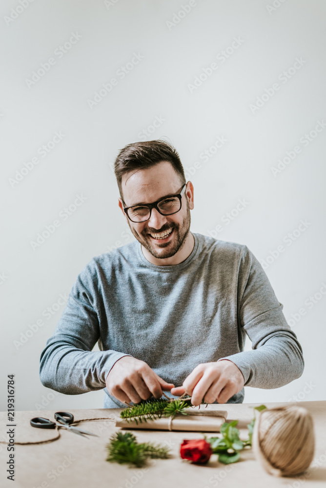 微笑的年轻人包装礼物的肖像。情人节、生日或周年纪念概念。