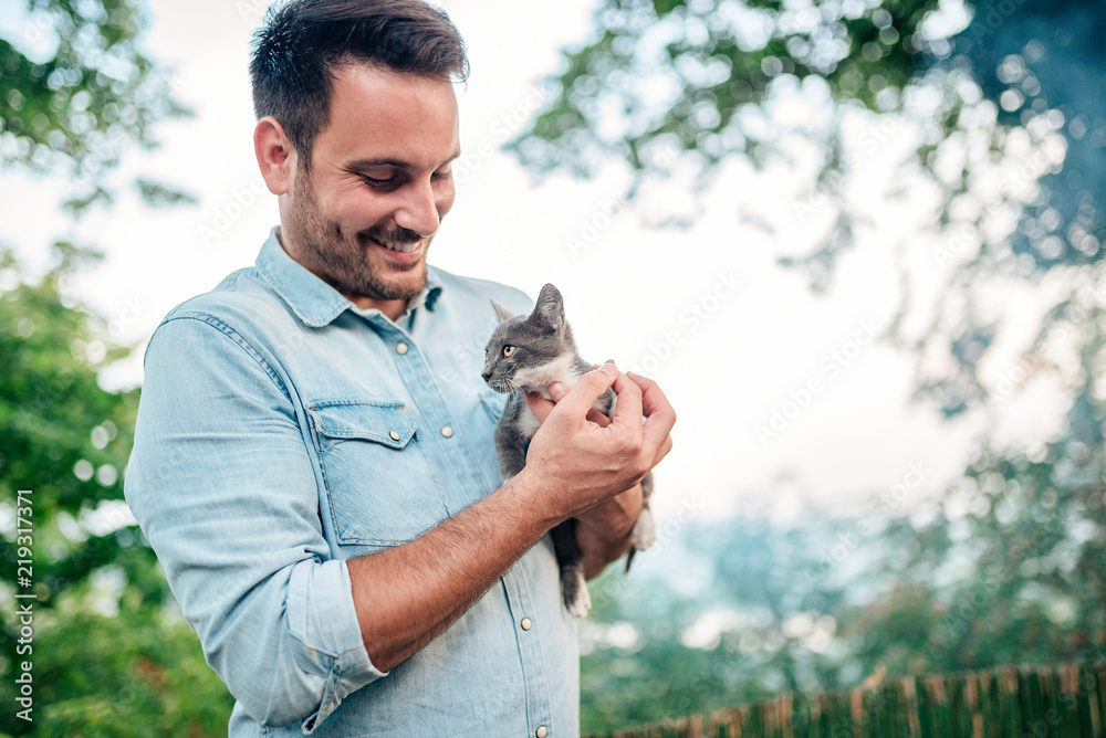 英俊的男人在户外抱着一只可爱的猫。