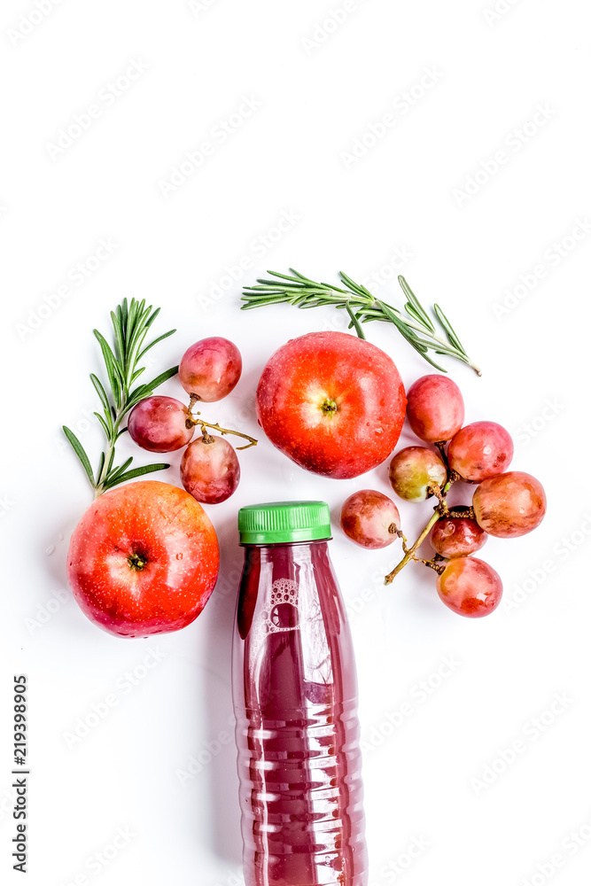 apple and grape juice in bottle on white background top view moc